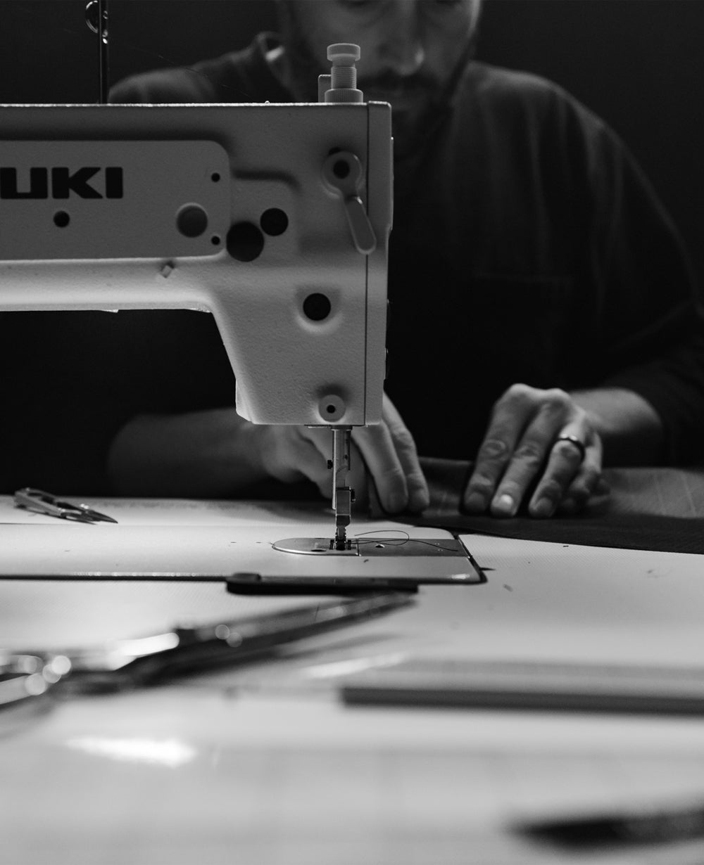 Black and white image of man at a sewing machine
