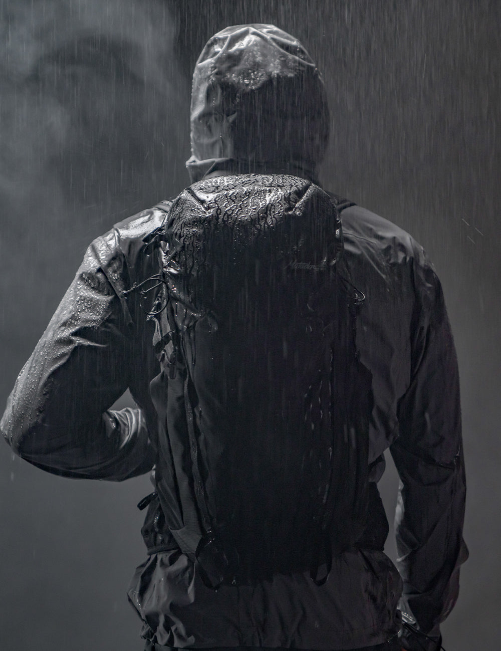 person in moody rain scene wearing black backpack