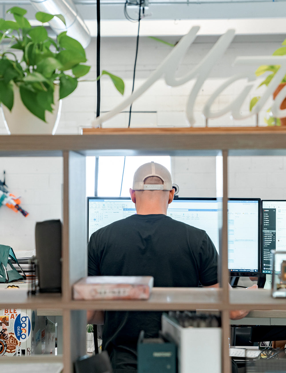 photo taken through bookshelf squares of man on a computer