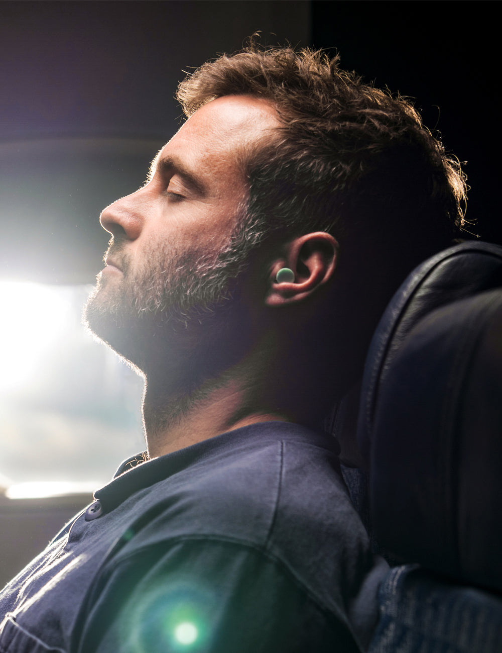 man wearing ear plugs, sleeping on airplane