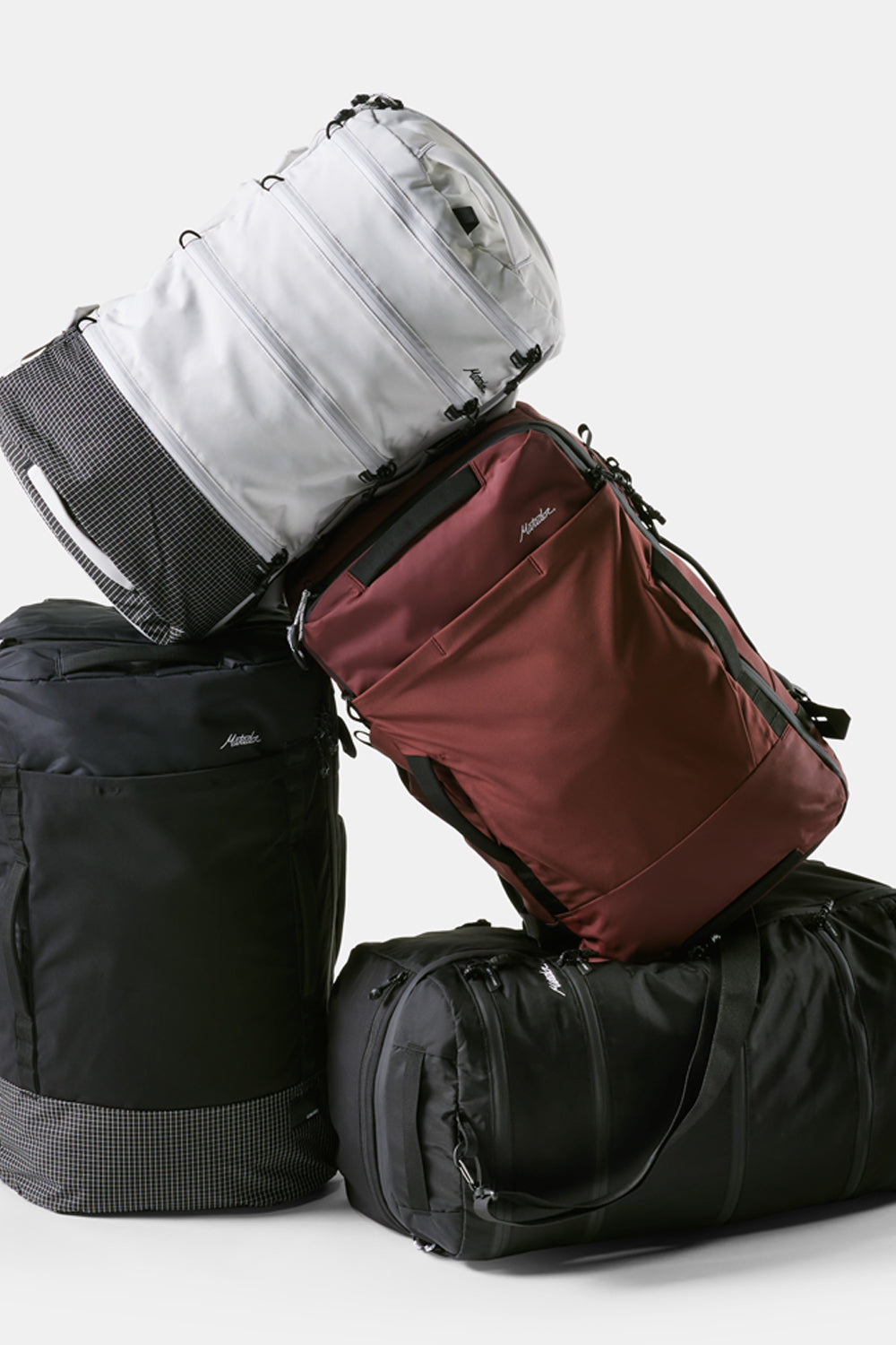Pile of white, garnet, and black travel packs on light gray background