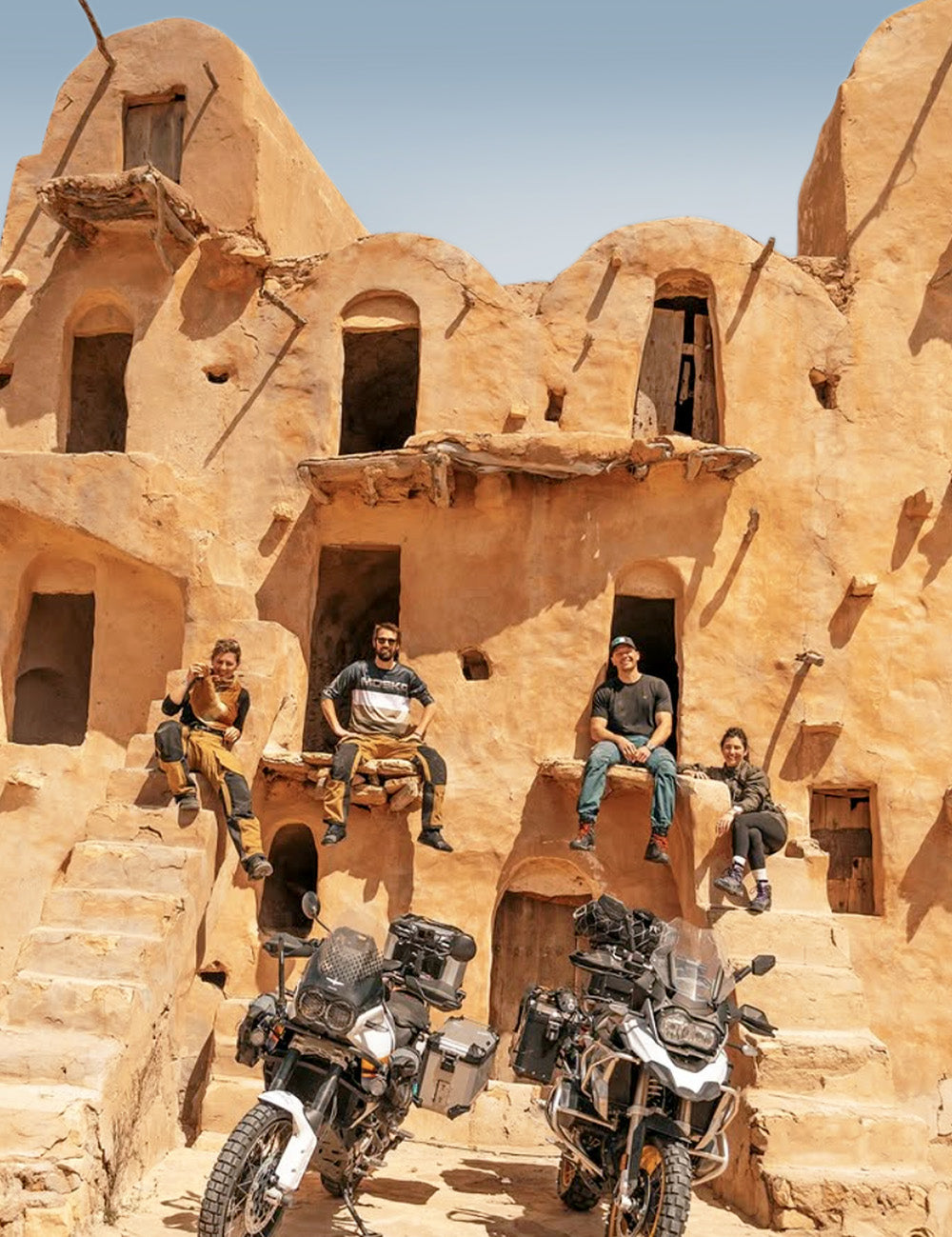 4 people with 2 motorcycles, sitting on Tunisian ruins