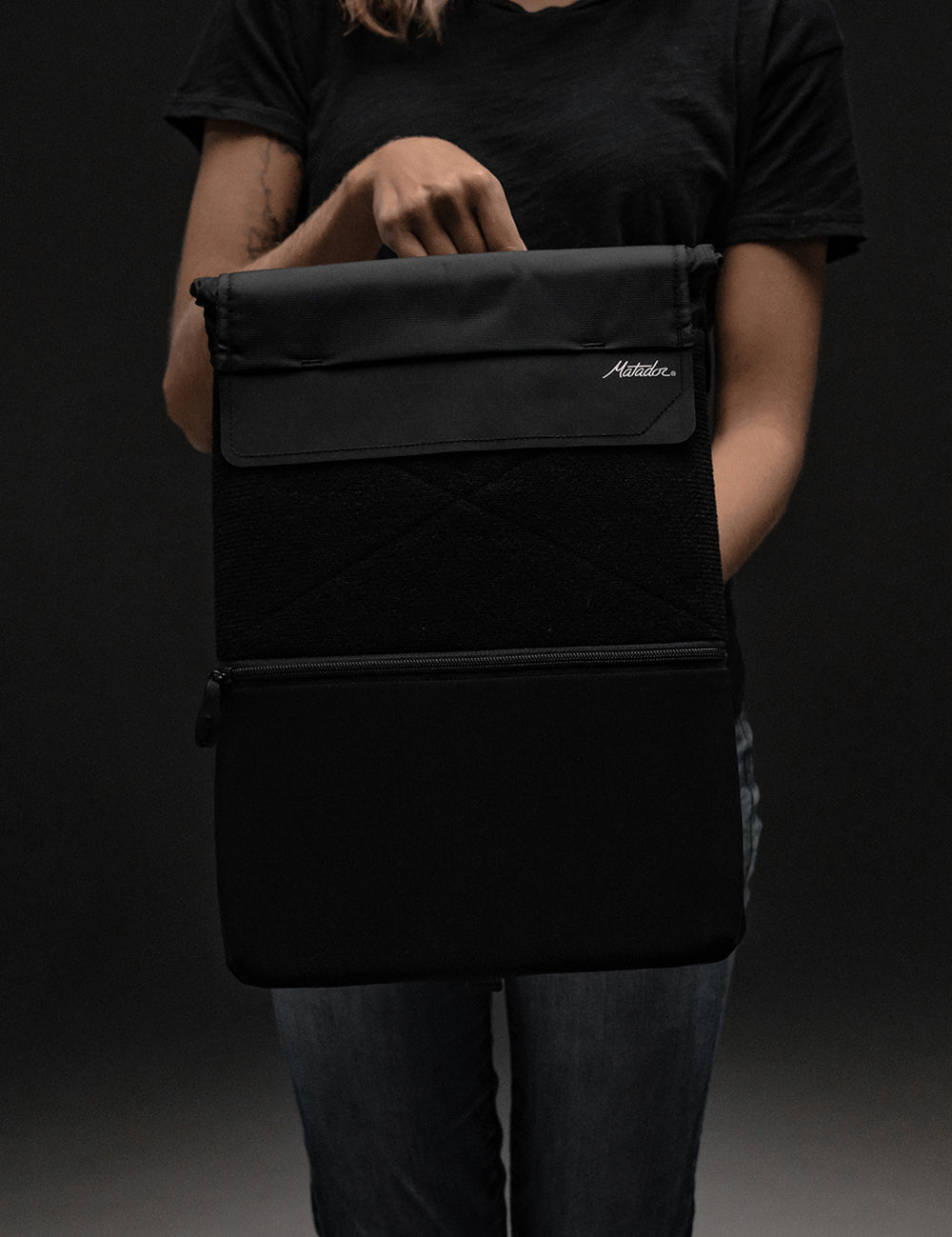 person in dark studio holding laptop base layer