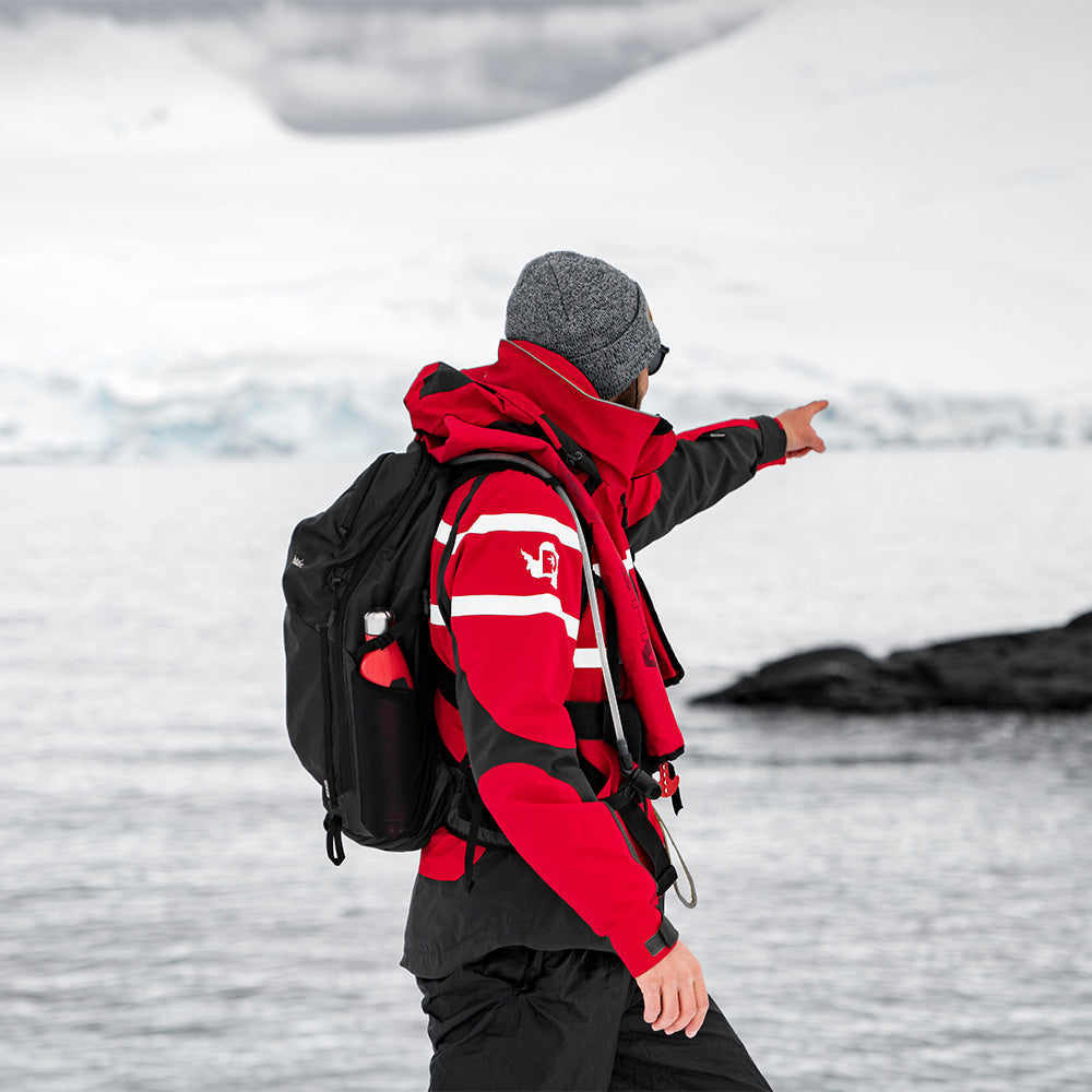 Man in red jacket, wearing a black backpack in arctic scene