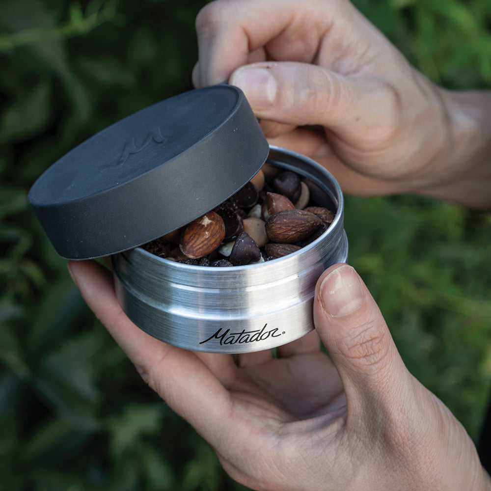 hands opening canister to reveal trailmix