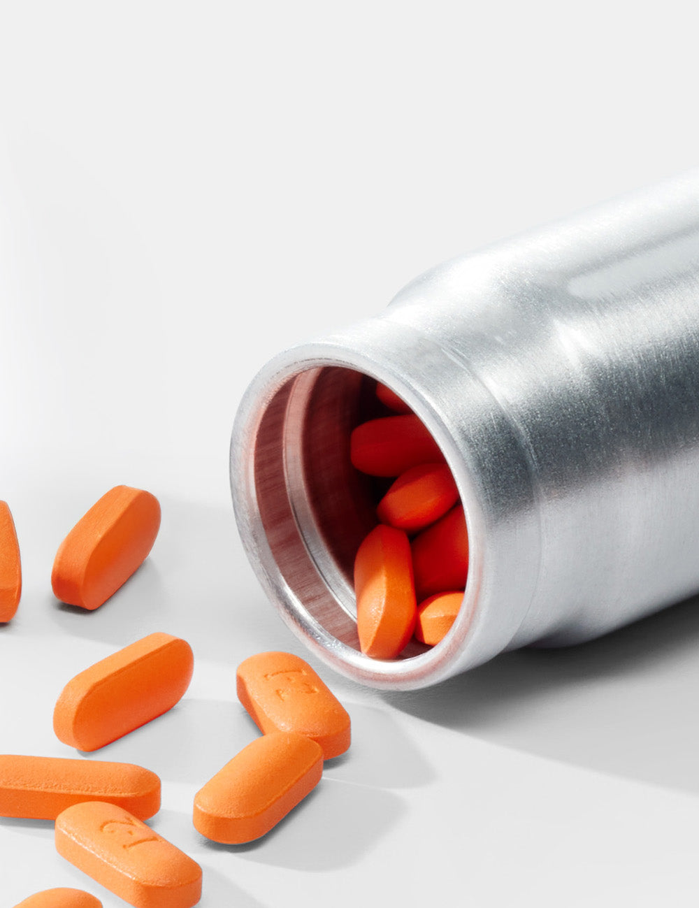 close up view of orange pills coming out of small canister
