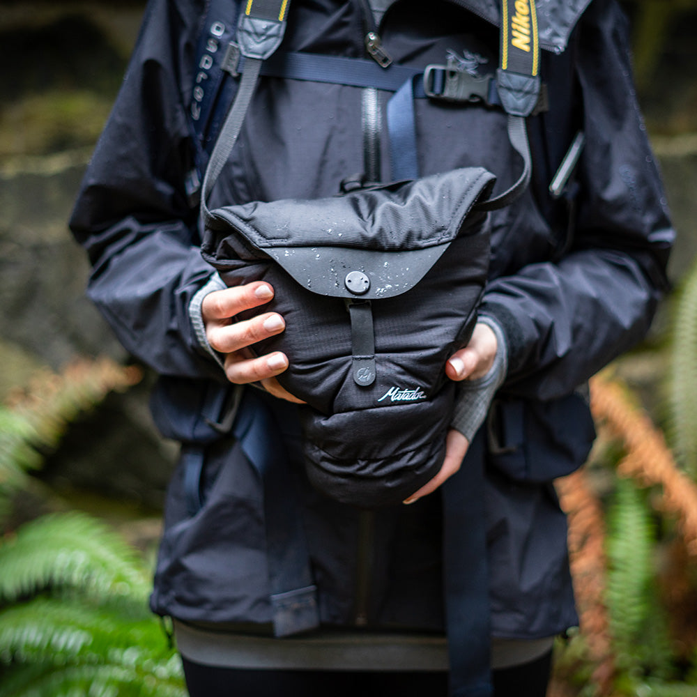 holding camera base layer in damp forest