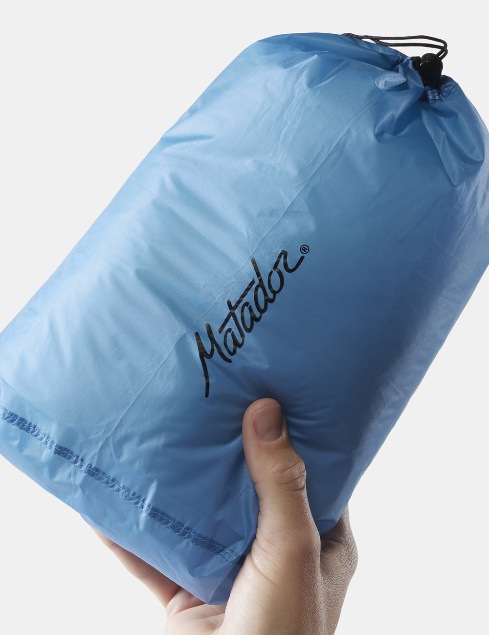 hand on white background holding up stuffed blue bag