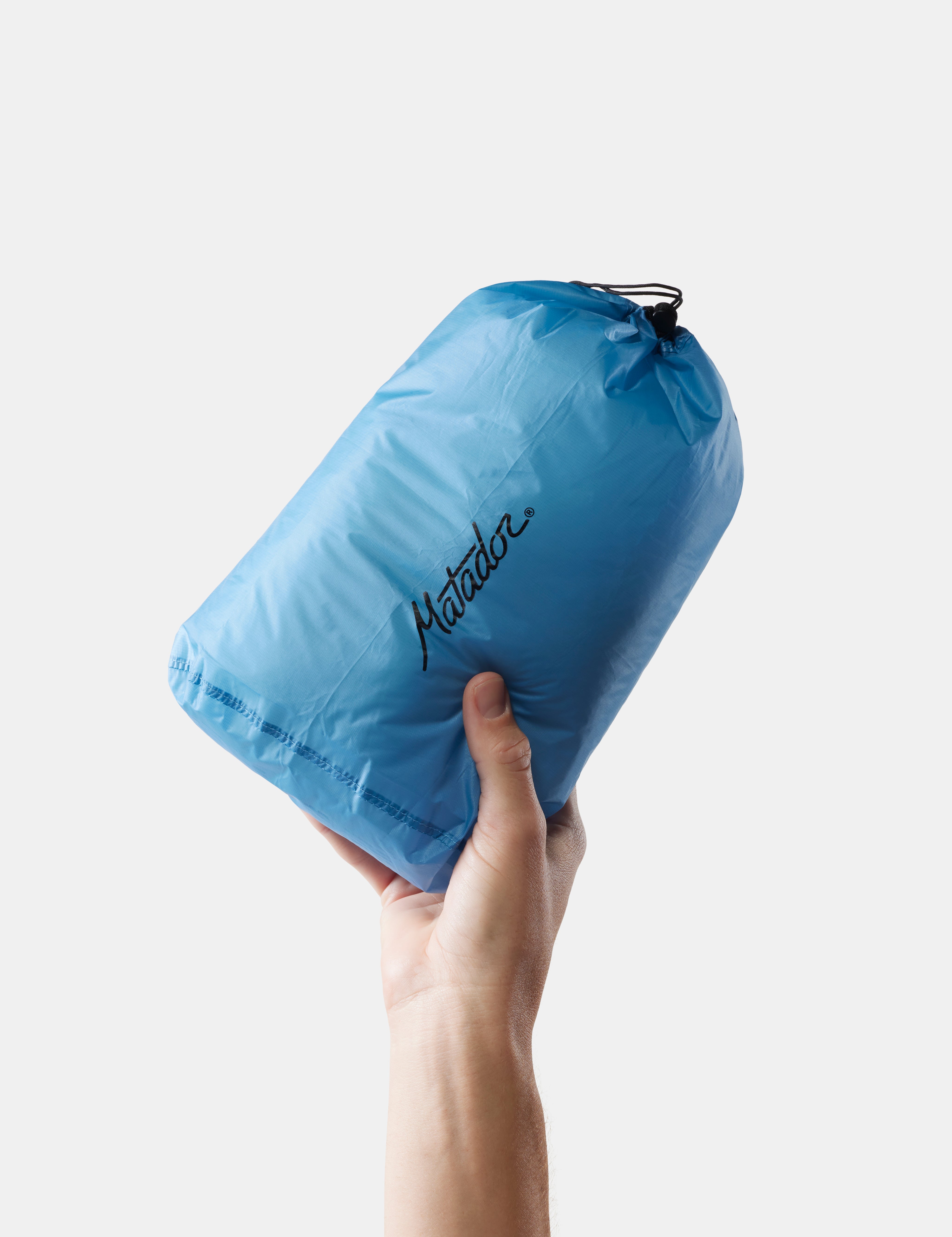 Hand holding a blue Matador droplet against a white background