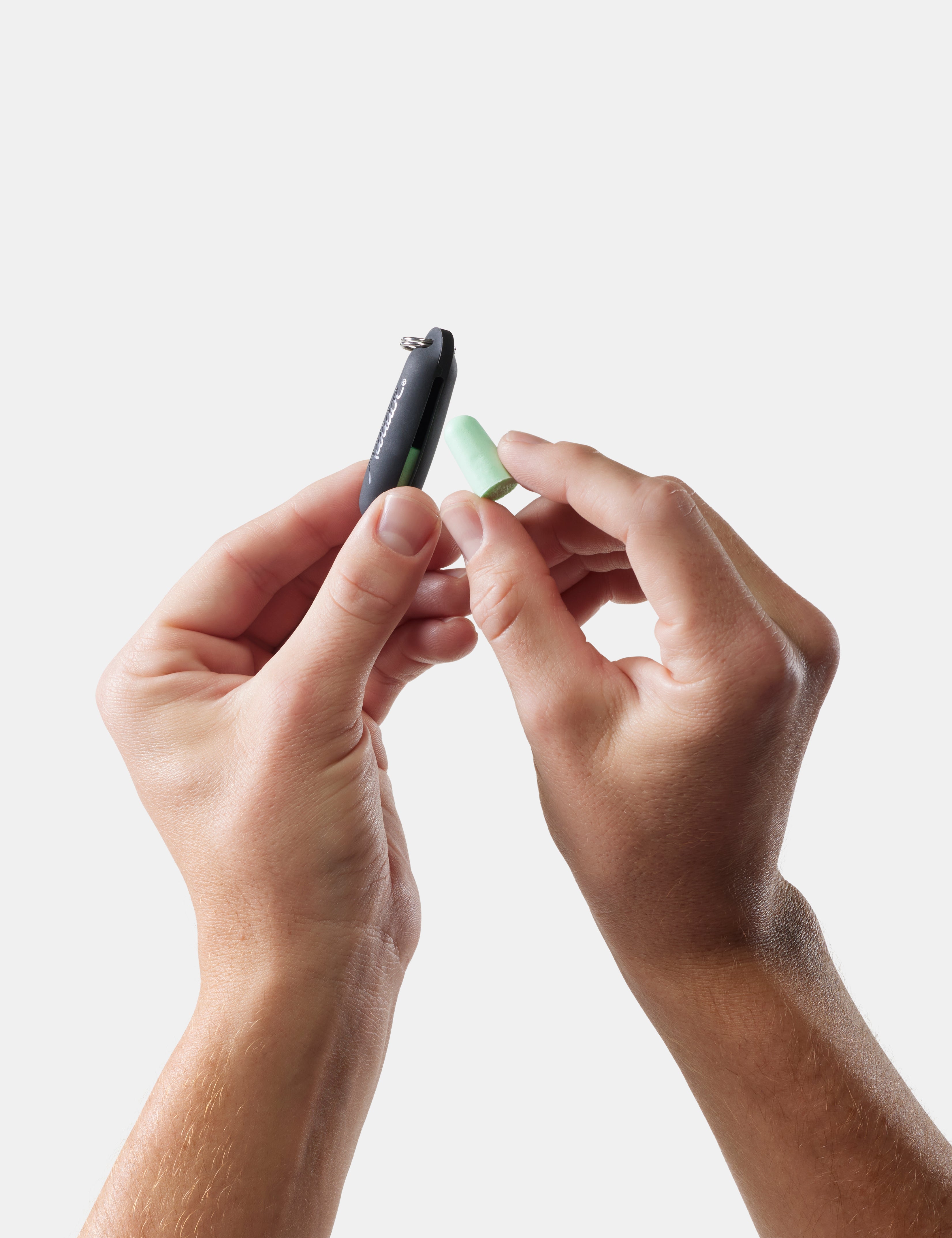 hands putting earplug into black pouch on white background