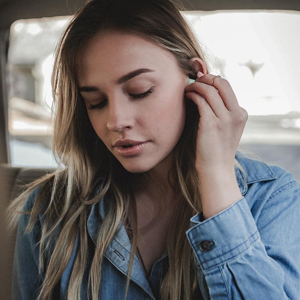 blonde woman putting earplugs in