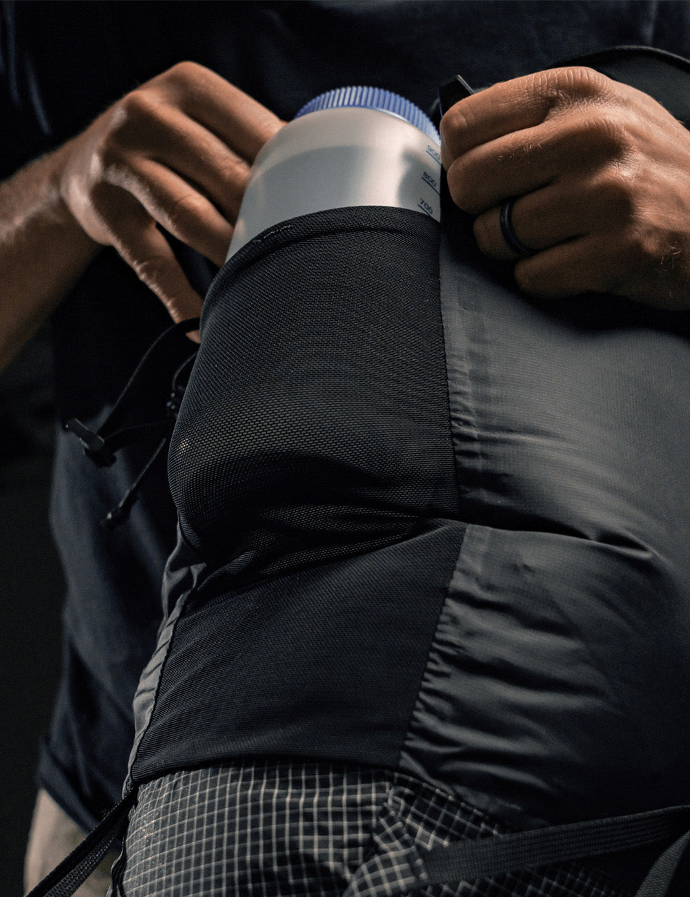 putting water bottle in side pocket of black backpack