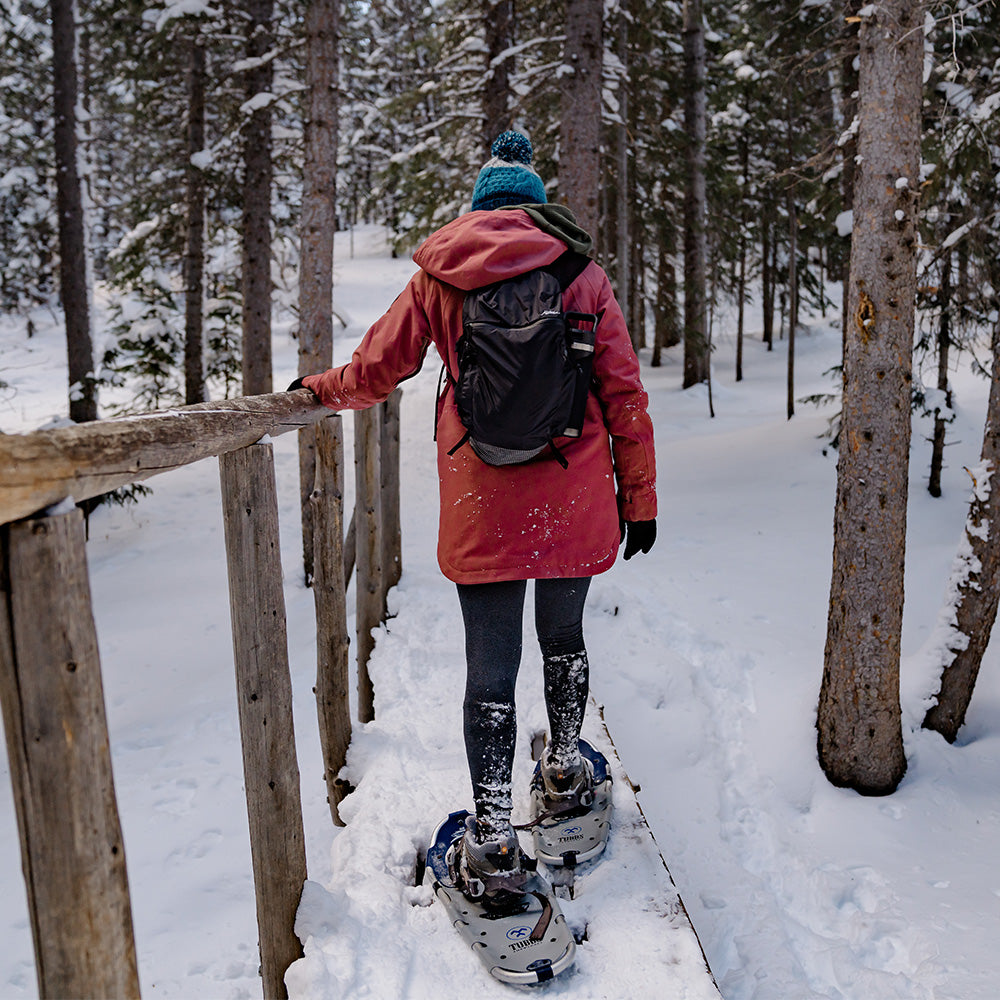 woman snowshoeing in winter scene with black backpack