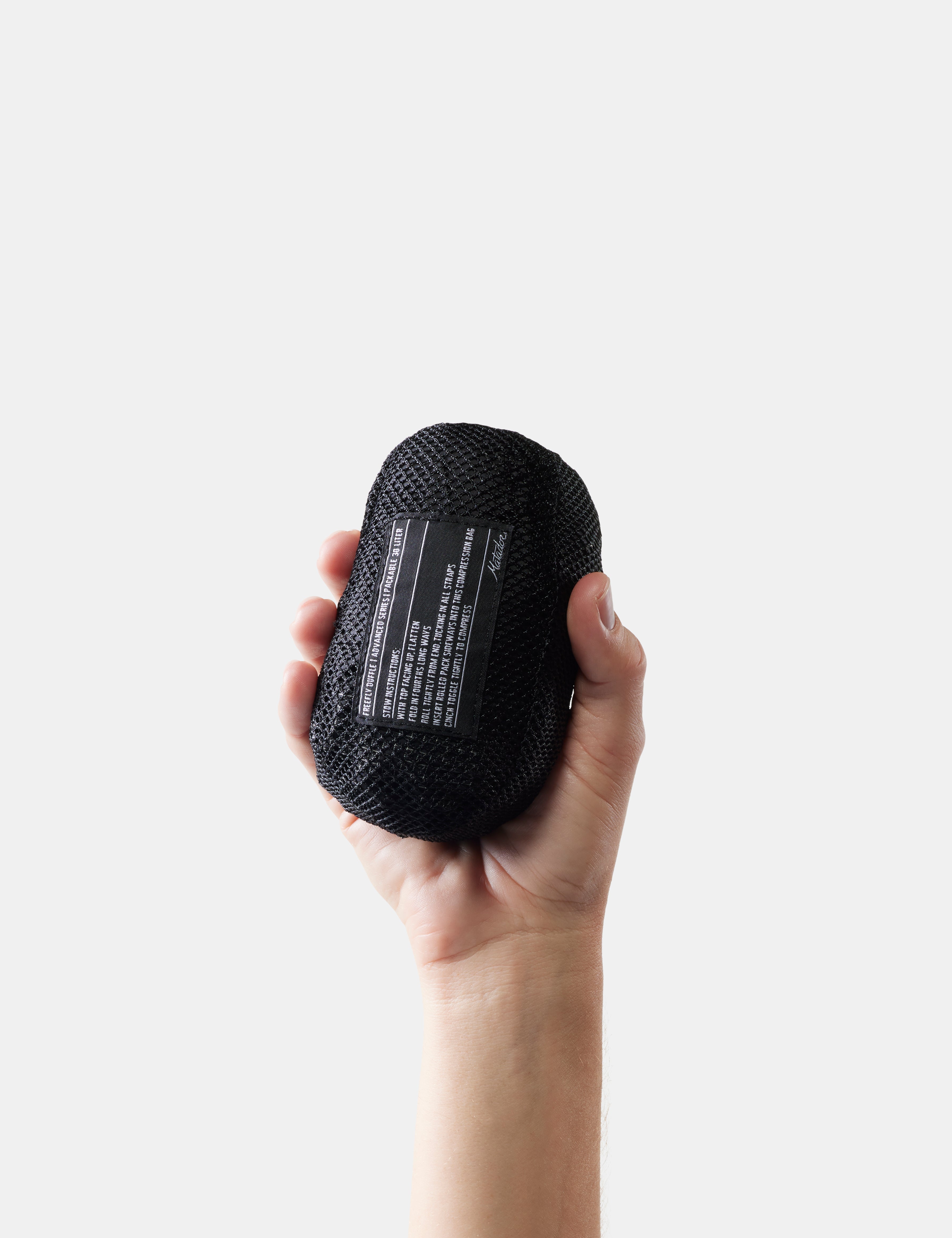 Hand holding a black textured object against a white background