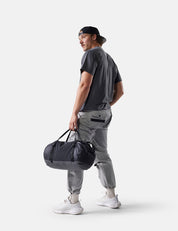 Man holding a black duffel bag against a white background