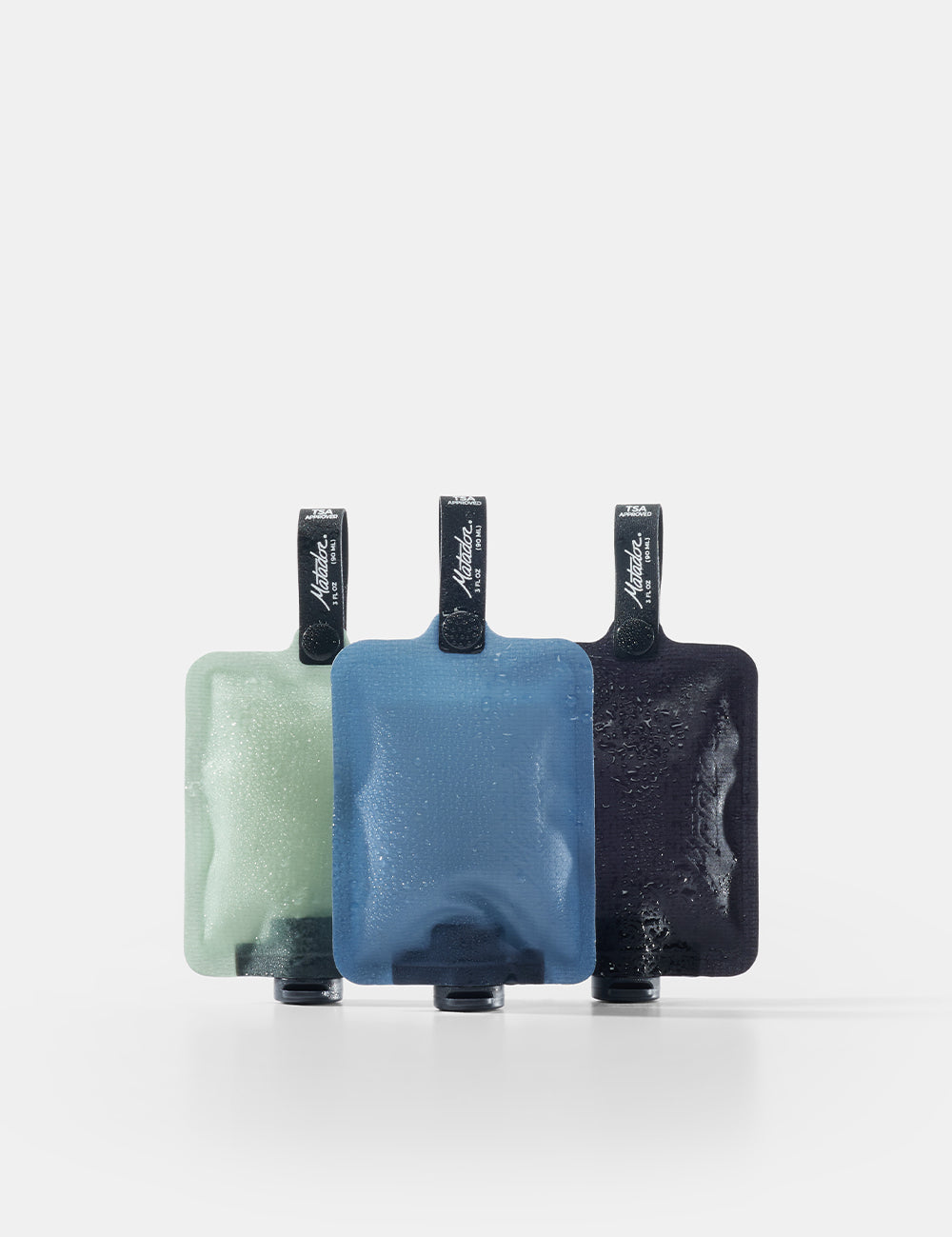 Three toiletry bottles in green, blue, and black on a white background