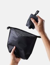 Person holding a black pouch with a smaller black item inside against a light gray background