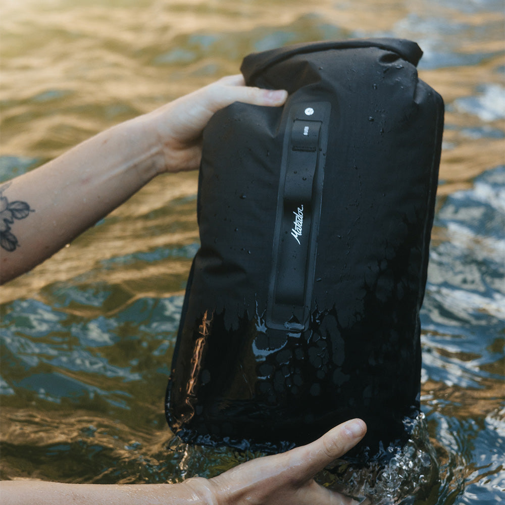 hands holding dry bag about to be submerged in water
