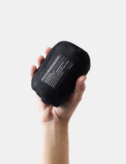 Hand holding a black textured object with a label on a light gray background