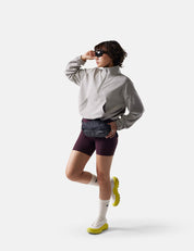 Person wearing a gray jacket, maroon shorts, and white sneakers on a white background
