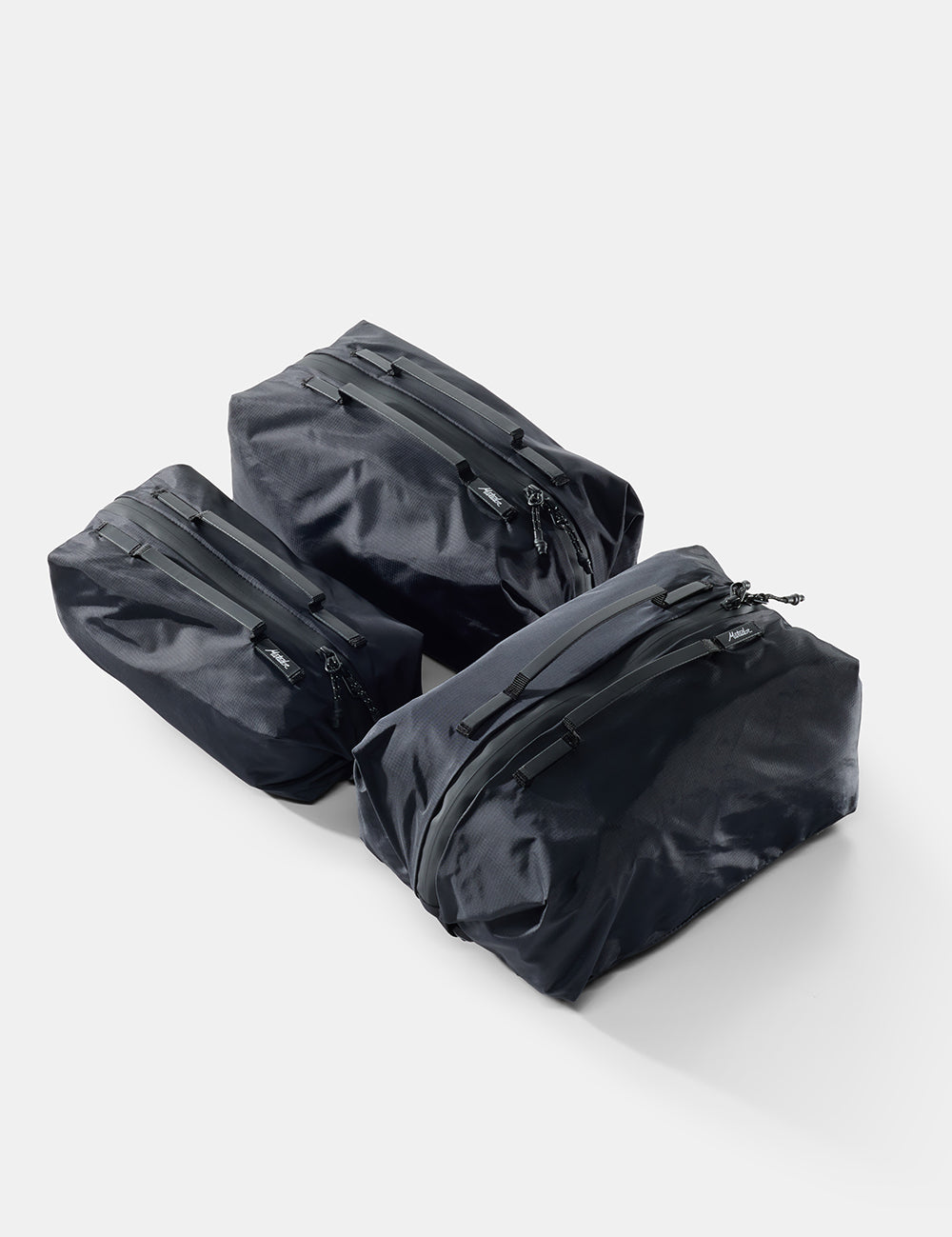 Three black travel bags with zippers on a white background