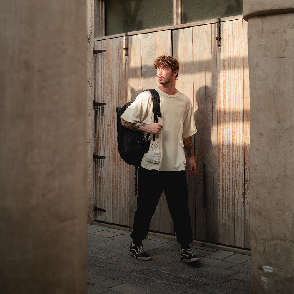man in shadowy street wearing black backpack
