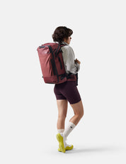 Person wearing a large red backpack on a white background