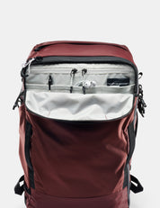 Maroon backpack with open front compartment on a light gray background