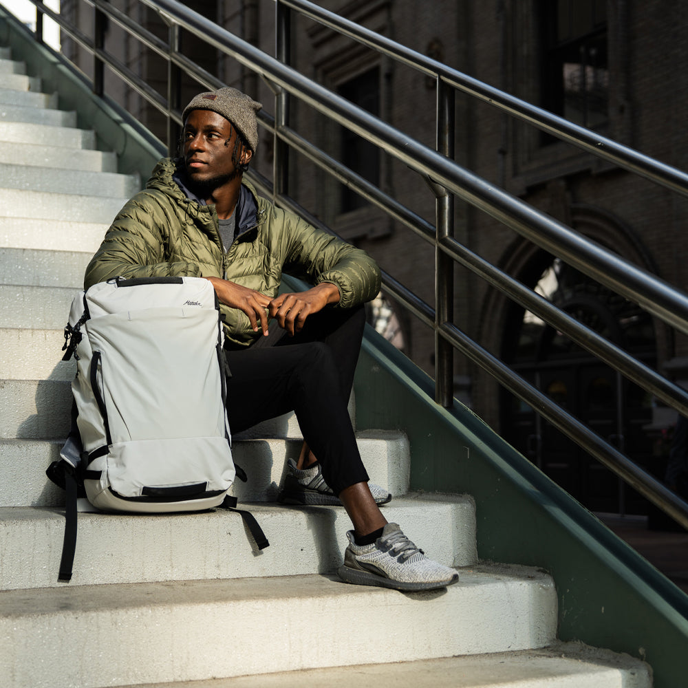man sitting on city steps with white backpack