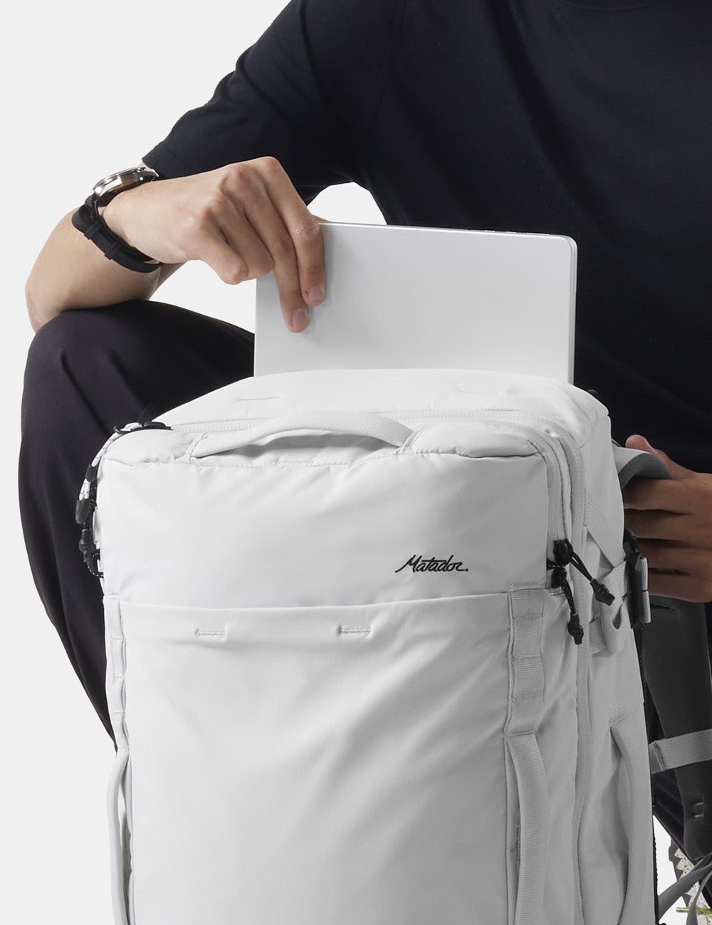 pulling laptop out of white backpack