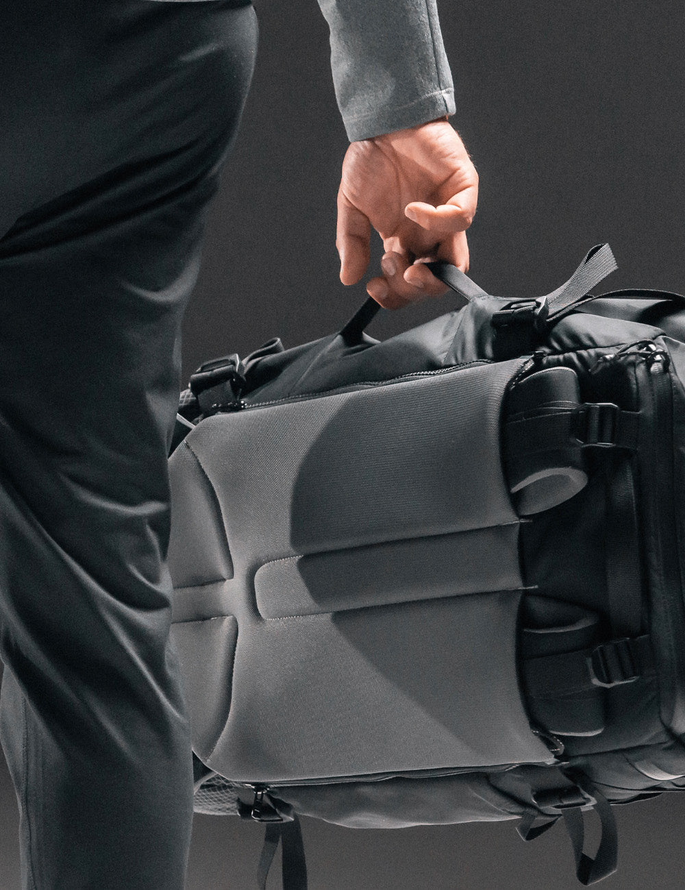 man carrying black backpack by side handle