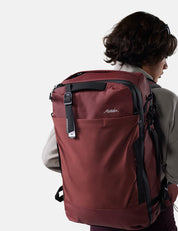 Person wearing a red backpack with a visible brand logo on a white background