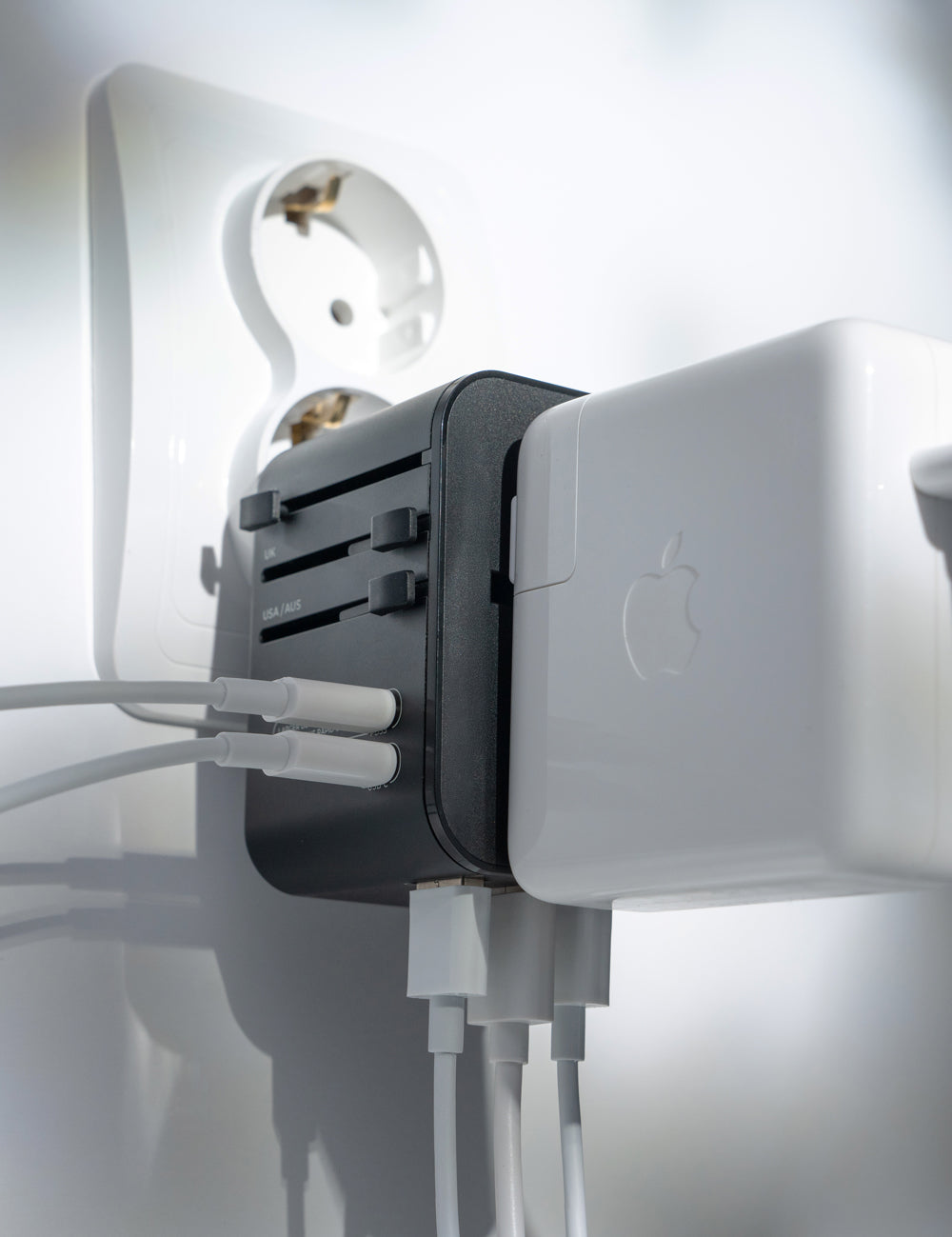 black travel adapter plugged into European socket with 6 cords plugged into it.