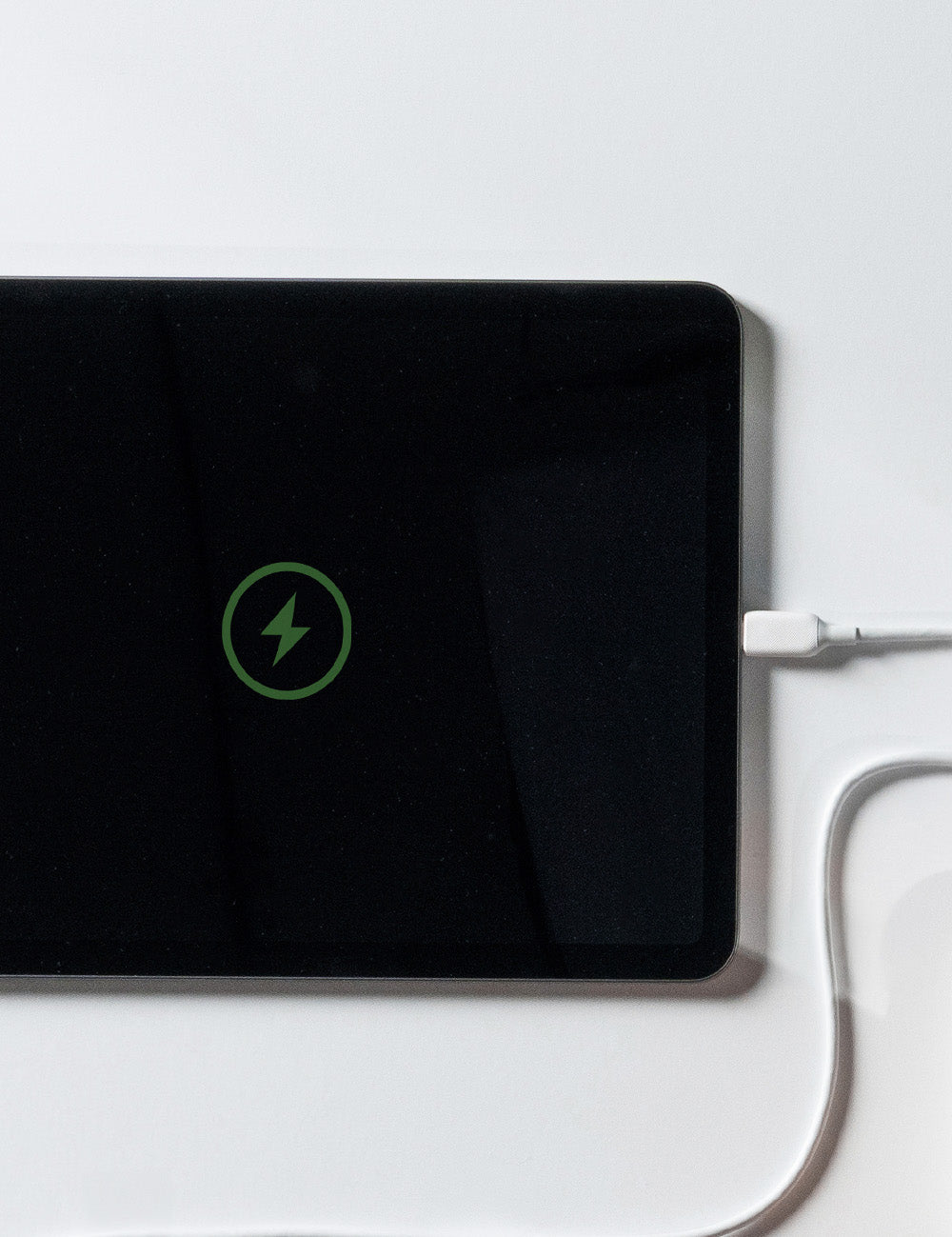 ipad with charge symbol, plugged in on white background