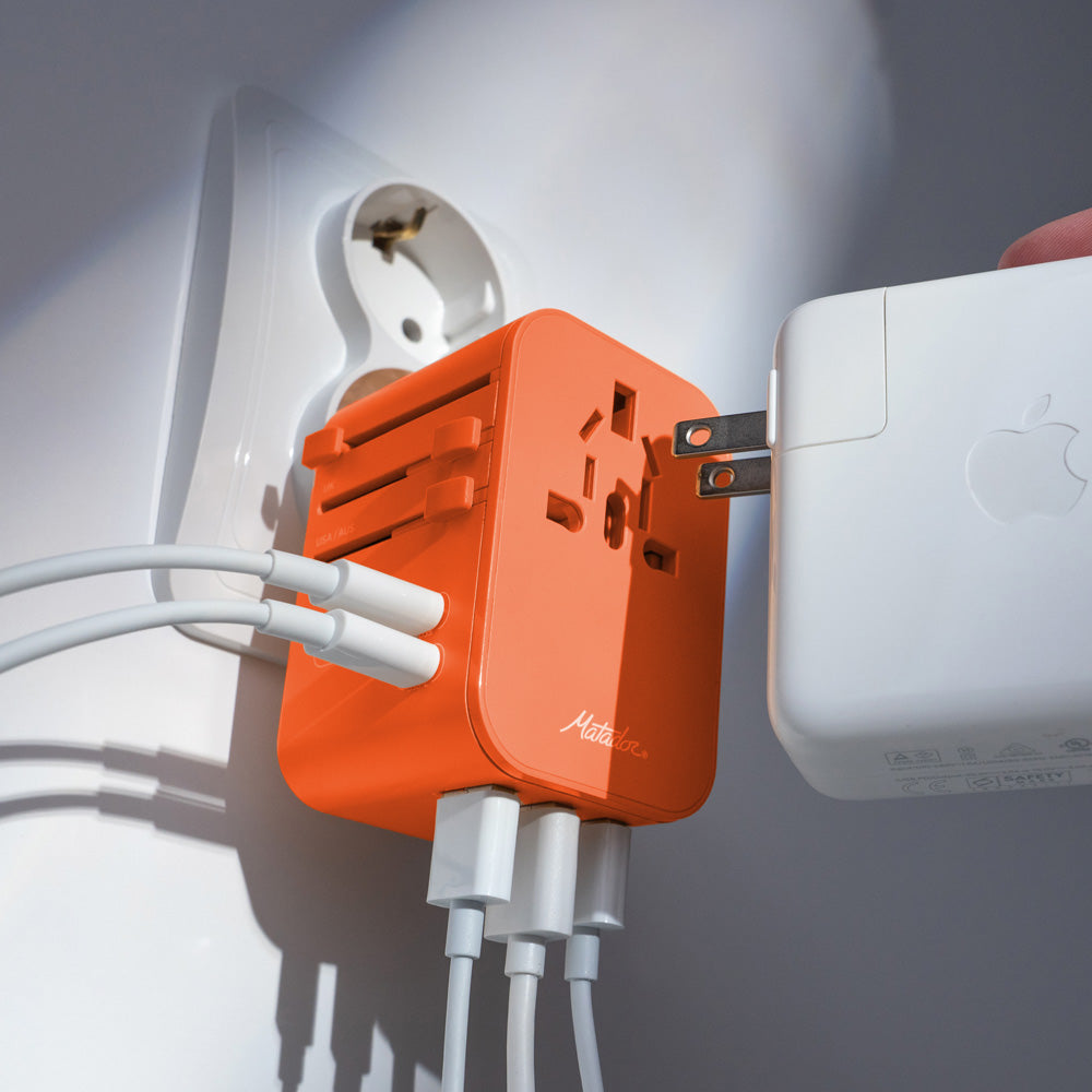 Close up view of orange travel adapter plugged into EU outlet with all 6 plugs being used