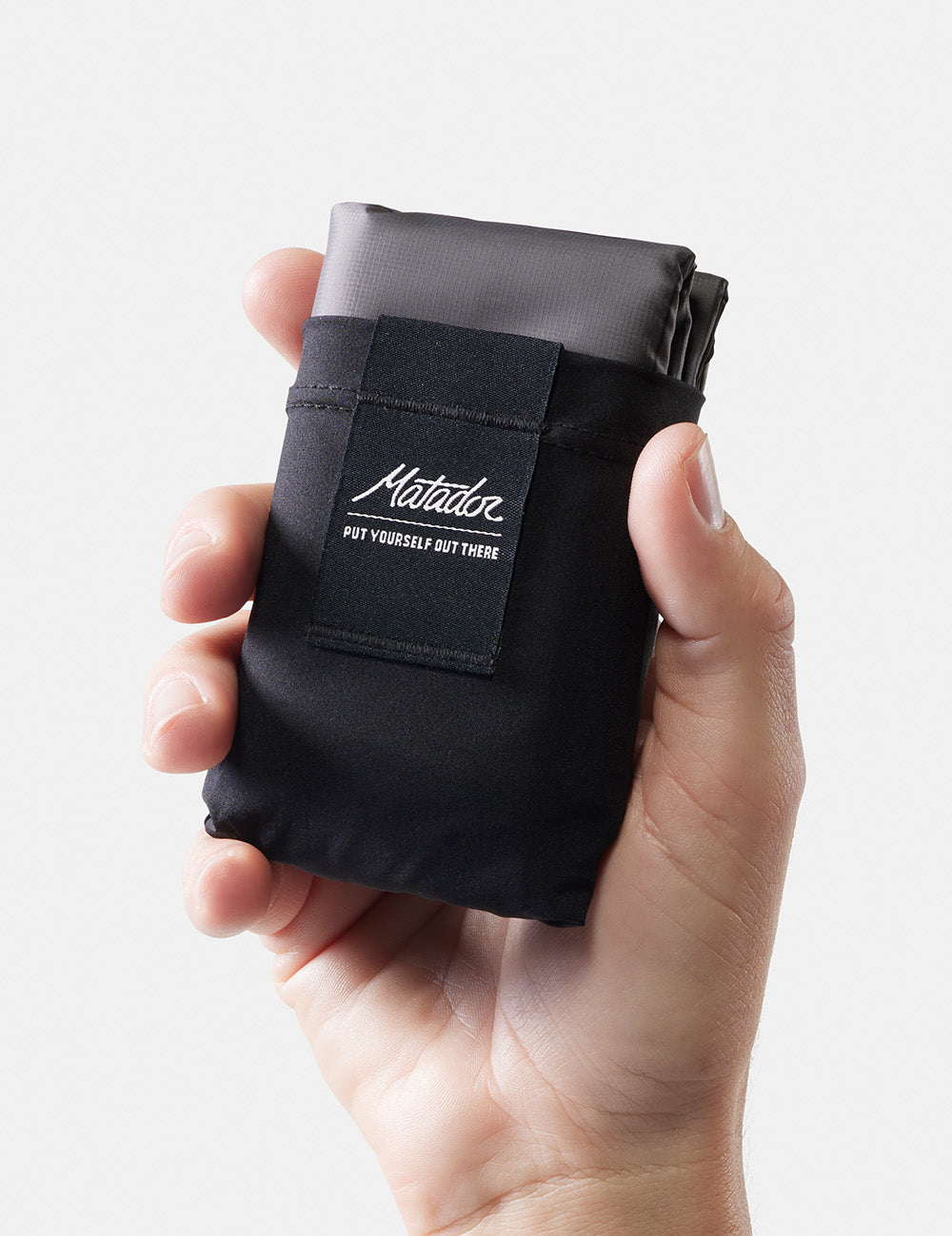 hand holding up packed up pocket blanket