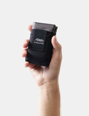 Hand holding a black pouch with a brand logo on a white background