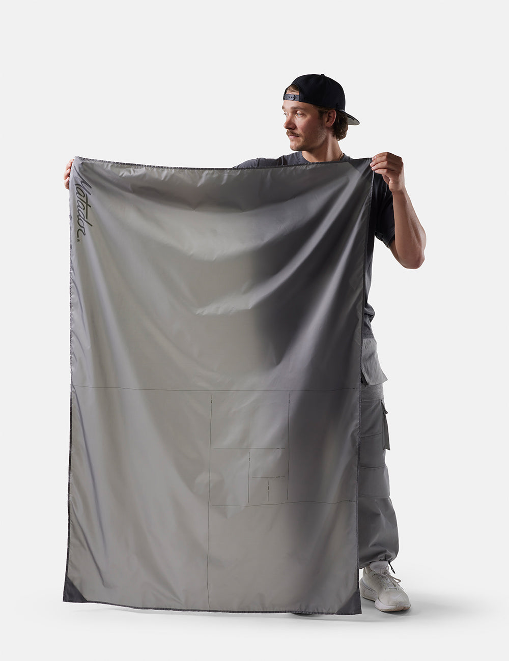 Person holding a large gray fabric against a white background