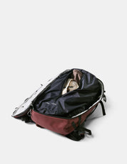 Open backpack with dirty clothes on a light gray background