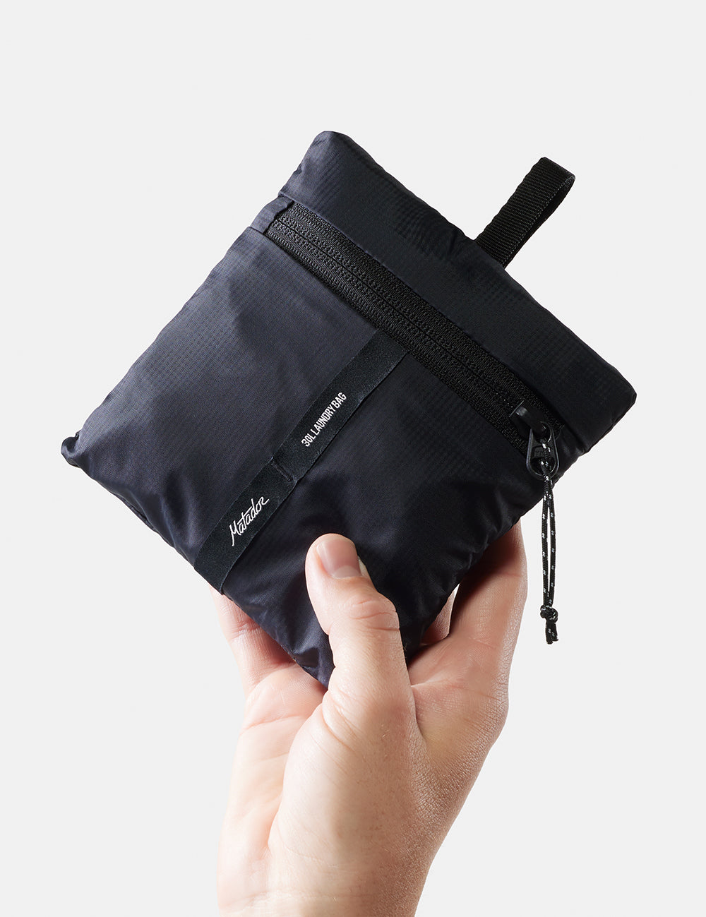 hand holding packed up laundry bag on white background