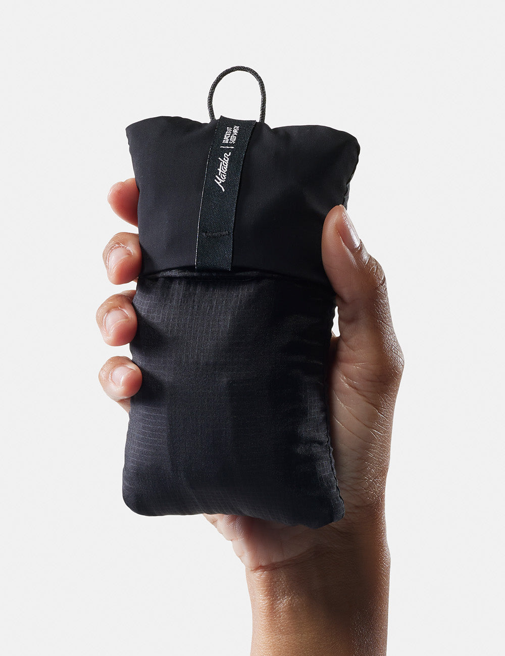 hand holding packed up sleep mask on white background