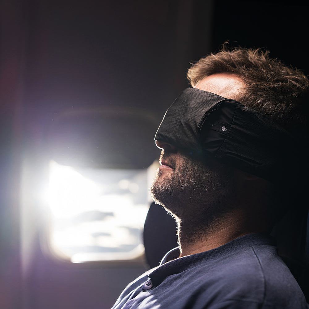 man wearing eye mask, sleeping in bright airplane