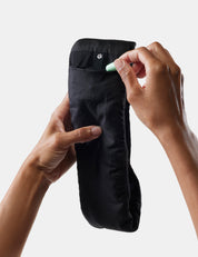 hand placing earplugs in black sleepmask on white background