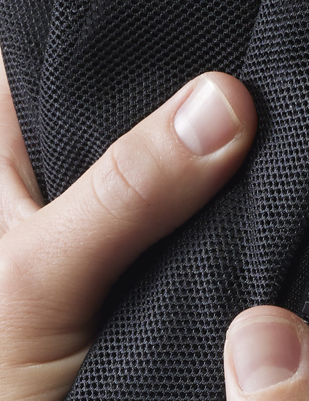 close up view of thumbs touching mesh material