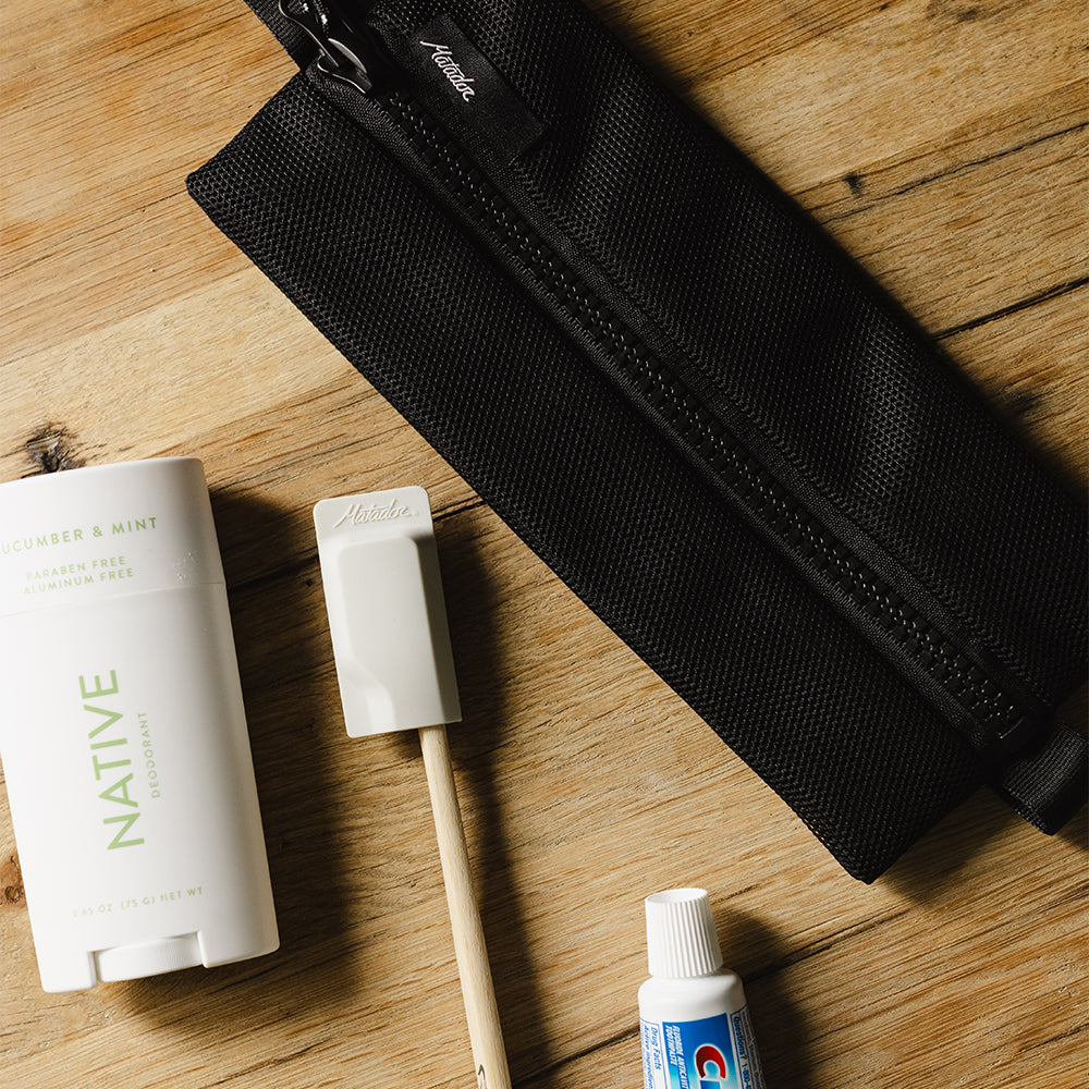 black mesh bag on wooden table with various toiletries 