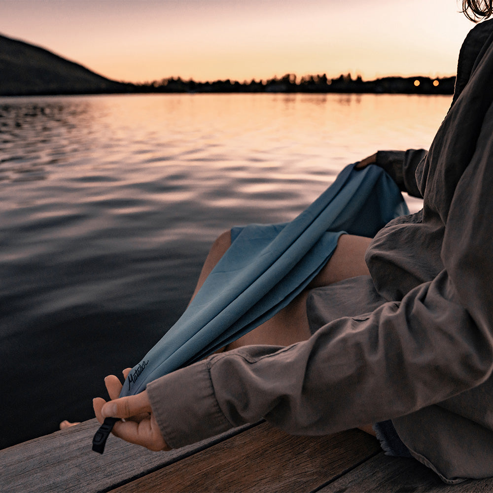 Woman sitting by a lake, holding slate towel