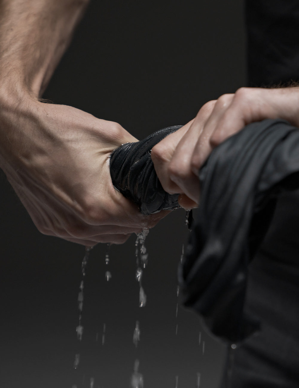 hands wringing water out of charcoal towel