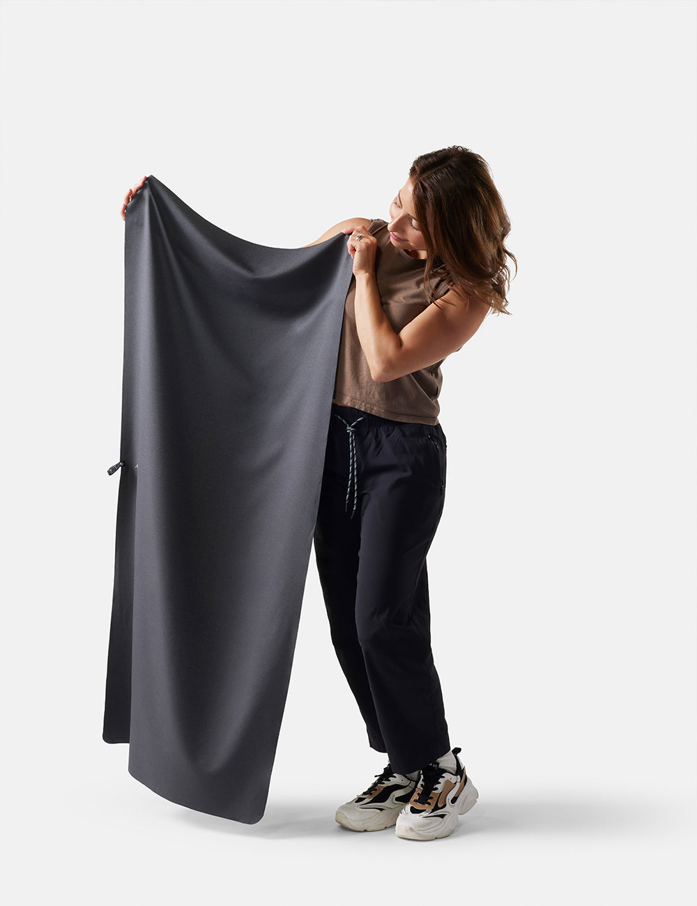 Person holding a large dark gray fabric against a white background