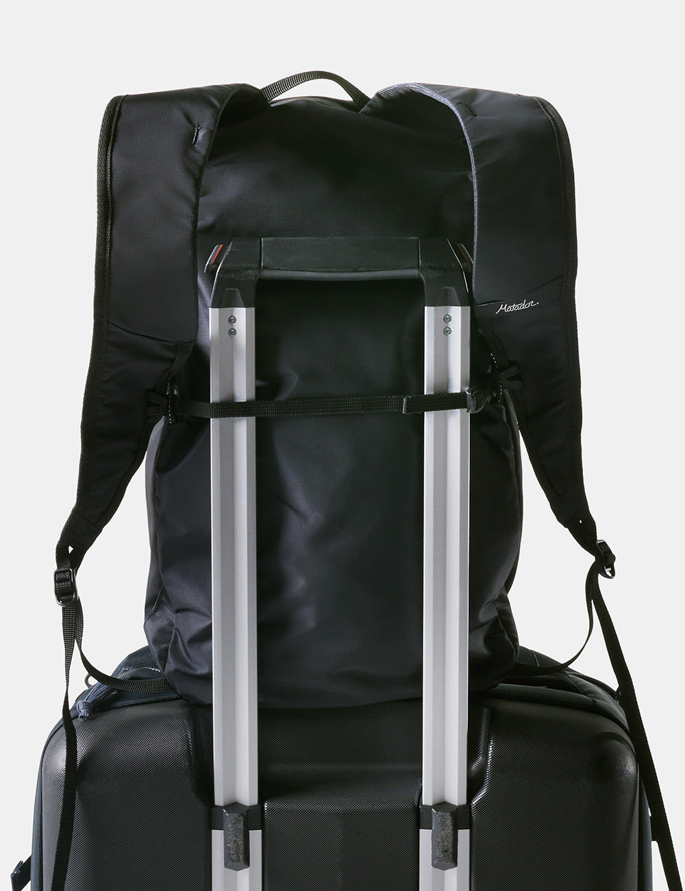 black backpack strapped onto hard luggage handle
