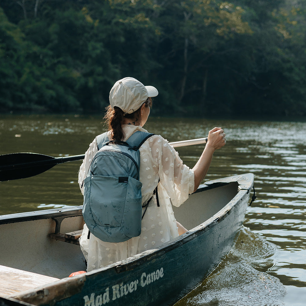 woman paddling a canoe, wearing a blue backpack
